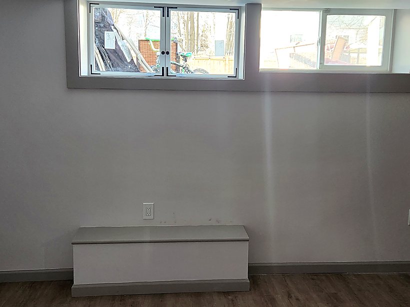 Finished basement bedroom wall with two egress windows installed and drywall complete
