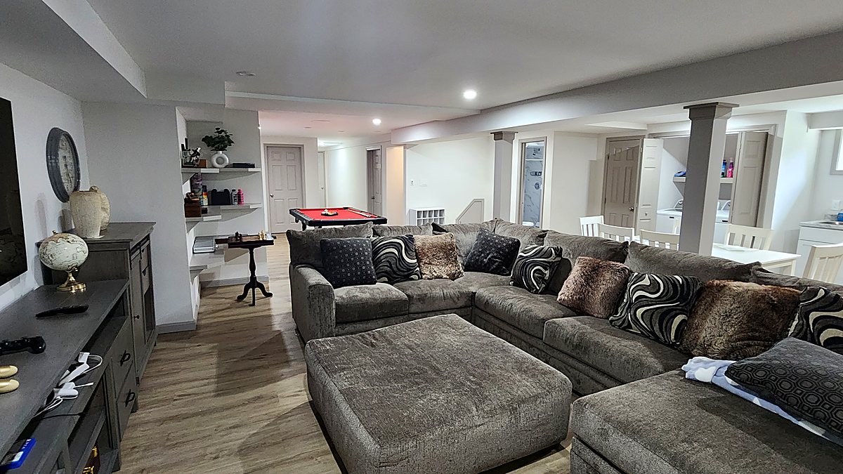 Finished basement living area with sectional seating and plank flooring, built by Vascontractors in Fairfield County, Connecticut