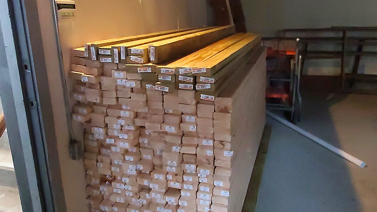 Framing lumber and building materials staged inside a basement before construction begins
