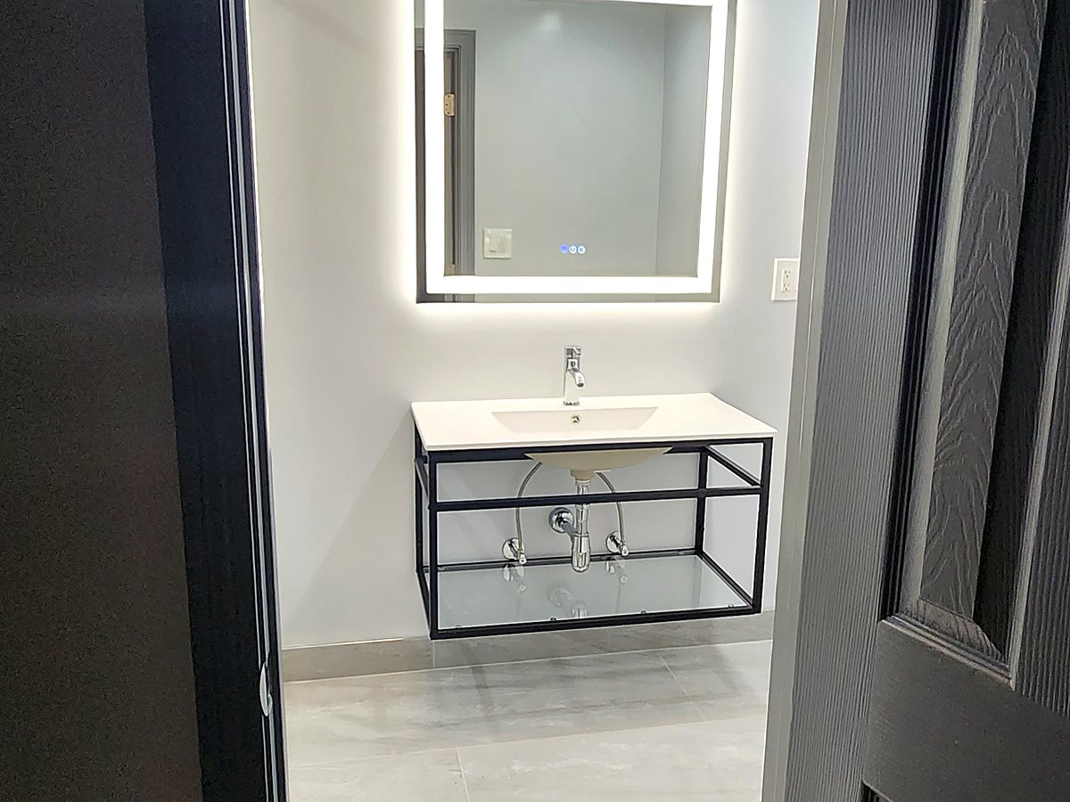 Finished basement bathroom in Bridgeport, CT with a floating vanity, metal frame, vessel-style basin and a backlit mirror