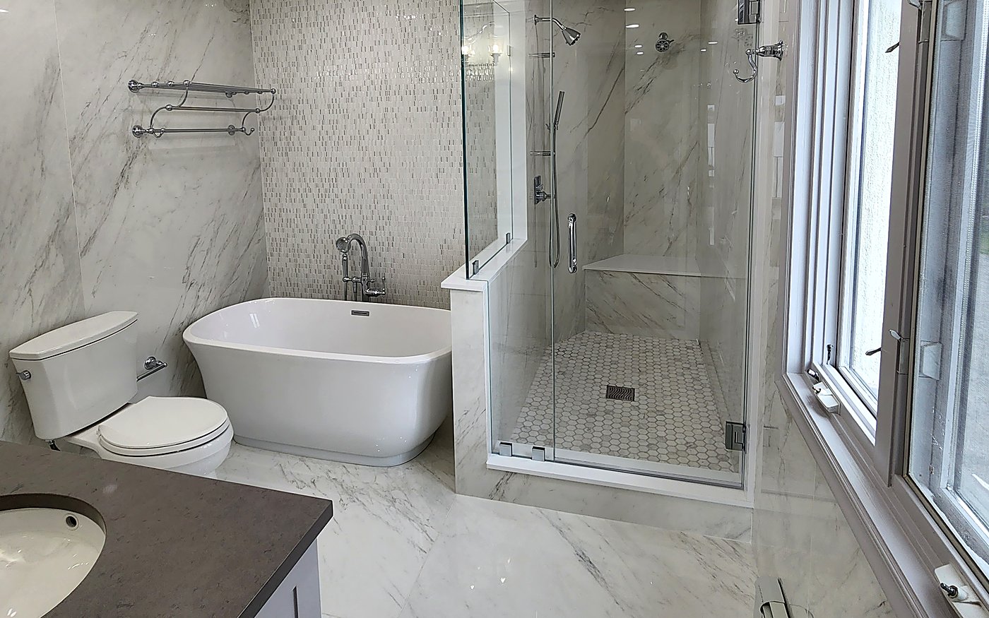 Finished master bathroom in Stamford, CT with marble-look porcelain, a freestanding tub, a glass shower and a grey quartz vanity